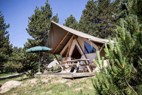 Een safaritent genaamd Canadian tent bij Huttopia Font-Romeu in Frankrijk, omgeven door natuur en dennen.