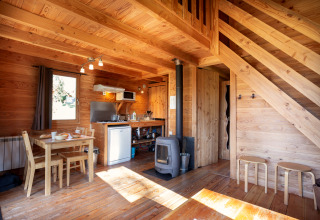 Houten interieur van Chalet 'The Cabin' bij Huttopia Font-Romeu in Frankrijk met eettafel en houtkachel.
