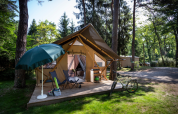 Tienda safari Trappeur en Huttopia Font-Romeu, Francia, con terraza, bicicleta y sombrilla en el bosque.
