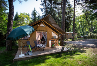 Tienda safari Trappeur en Huttopia Font-Romeu, Francia, con terraza, bicicleta y sombrilla en el bosque.