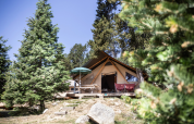 Safari-Trappeur-Zelt auf Huttopia Font-Romeu in Frankreich, umgeben von Bäumen und natürlicher Landschaft.