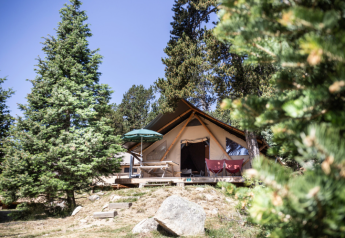 Safari Trappeur-telt ved Huttopia Font-Romeu i Frankrig, omgivet af grønne træer og naturlig skønhed.