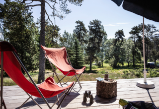 Relaxing view from a Trappeur safari tent at Huttopia Font-Romeu, France, with red chairs and forest scenery.