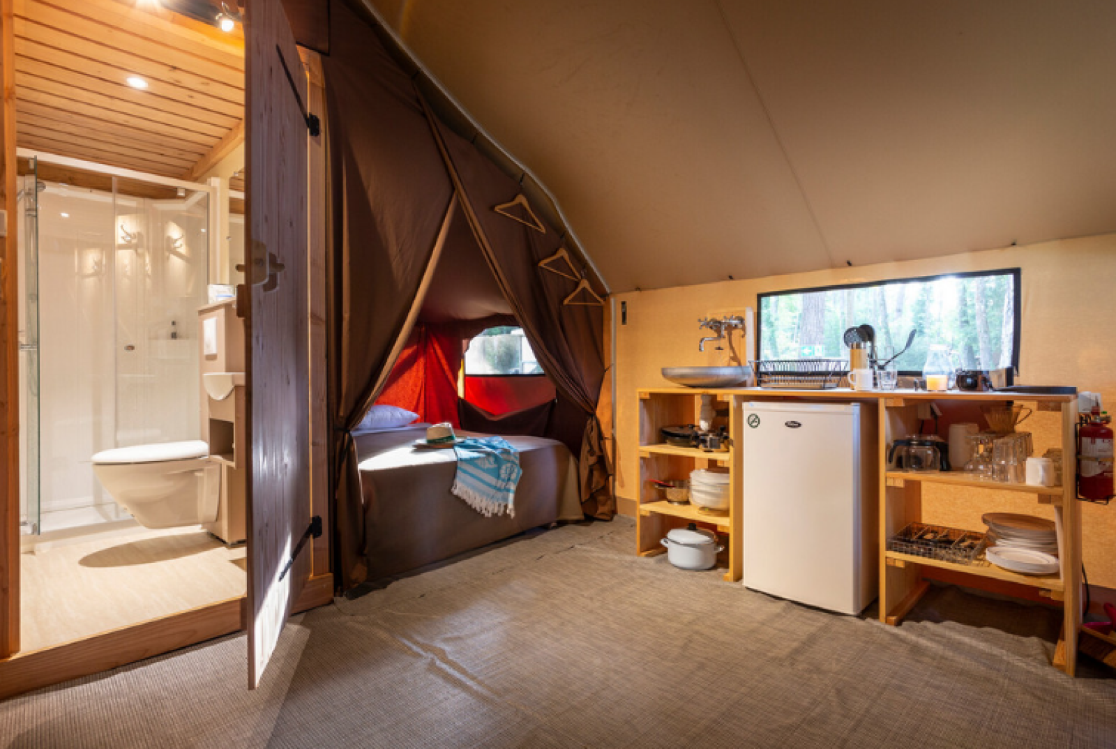 Interieur van een Trappeur safaritent bij Huttopia Font-Romeu, Frankrijk, met badkamer, keuken en bed.