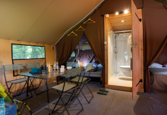 Interior de una espaciosa tienda safari Trappeur en Huttopia Font-Romeu, Francia, con comodidades modernas.