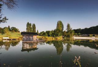 Reflejo de una cabaña sobre el lago en el parque Huttopia Vallée du Lot, Nouvelle-Aquitaine, Francia, al atardecer.