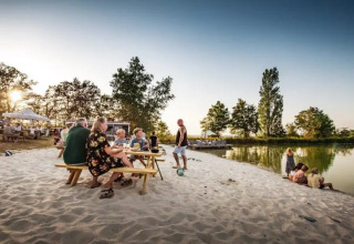 Folk nyder en solrig dag på sandstranden ved Huttopia Vallée du Lot feriested i Nouvelle-Aquitaine, Frankrig.