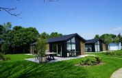 Moderne Velthorst-Lodges am Kagerplassen in den Niederlanden, umgeben von grünem Rasen und Bäumen.