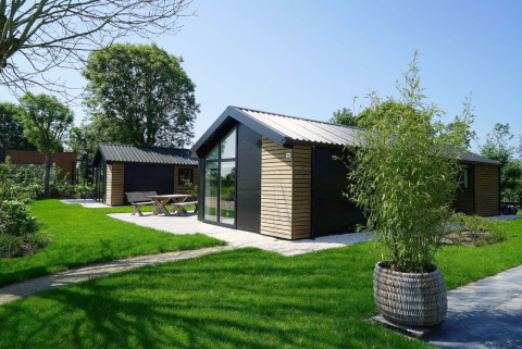 Moderne Velthorst lodge bij Kagerplassen in Nederland met gazon, grote raampartij en terras.