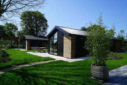 Moderna cabaña Velthorst en Kagerplassen, Países Bajos, con jardines verdes, terraza y gran ventanal.