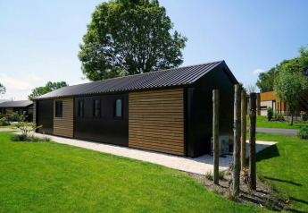 Moderno lodge Velthorst a Kagerplassen, Paesi Bassi, circondato da prato verde e alberi frondosi.