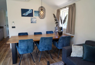 Eethoek in Velthorst-lodge bij Kagerplassen, Nederland, met blauwe stoelen, houten tafel en decoratie.
