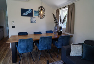 Comedor en la cabaña Velthorst en Kagerplassen, Países Bajos, con sillas azules y mesa de madera.