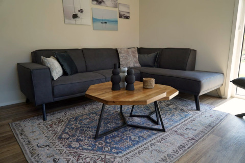 Moderne woonkamer in Lodge Velthorst bij Kagerplassen, Nederland, met grijze bank en houten tafel.