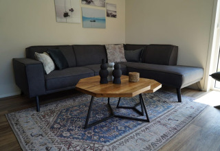Salon moderne du Lodge Velthorst à Kagerplassen, Pays-Bas, avec canapé gris, tapis et table bois.