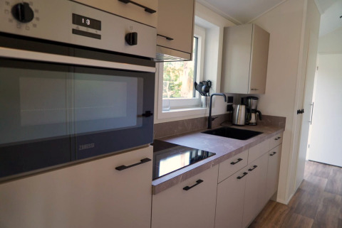 Moderne keuken in een Velthorst-lodge aan de Kagerplassen, Nederland, met oven, kookplaat en spoelbak.