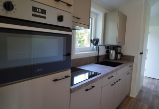 Cuisine moderne dans un lodge Velthorst à Kagerplassen, Pays-Bas, avec four, évier et plan de travail.