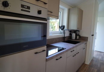 Moderne Küche in einer Velthorst-Lodge an den Kagerplassen, Niederlande, mit Herd, Spüle und Geräten.