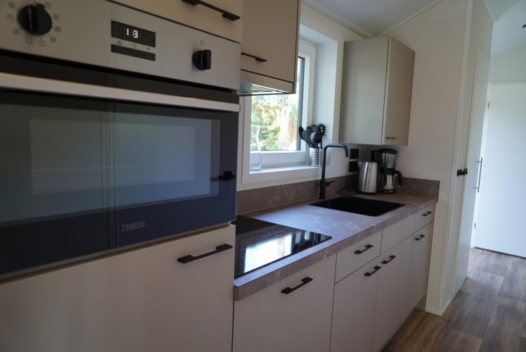 Moderne Küche in einer Velthorst-Lodge an den Kagerplassen, Niederlande, mit Herd, Spüle und Geräten.