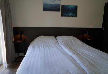 Schlafzimmer in der Velthorst-Lodge an den Kagerplassen in den Niederlanden mit Doppelbett und Dekor.