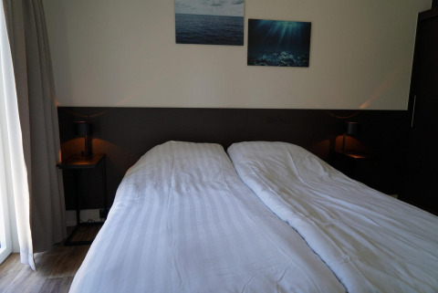 Chambre à la lodge Velthorst aux Kagerplassen, Pays-Bas, avec deux lits simples et décoration sobre.