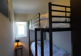 Petite chambre avec lits superposés au lodge Velthorst à Kagerplassen, Pays-Bas, fenêtre et lampe.