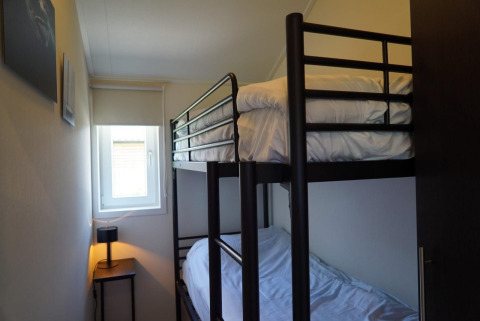 Petite chambre avec lits superposés au lodge Velthorst à Kagerplassen, Pays-Bas, fenêtre et lampe.