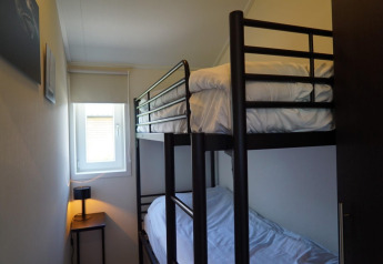 Petite chambre avec lits superposés au lodge Velthorst à Kagerplassen, Pays-Bas, fenêtre et lampe.