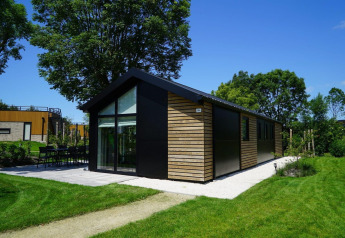 Lodge Velthorst à Kagerplassen aux Pays-Bas, entouré de pelouse verte et d’arbres sous un ciel bleu.