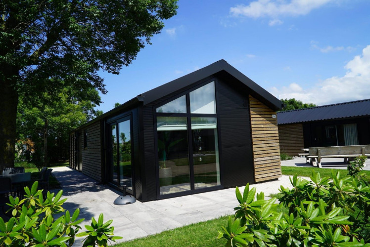 Moderne Lodge mit Holzverkleidung und großen Fenstern am Kagerplassen in den Niederlanden, im Grünen gelegen.