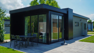 Lodge moderne Cube la Mer Wellness avec grandes baies vitrées, terrasse et pelouse sous ciel ensoleillé.