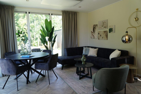 Salón moderno con mesa de comedor, plantas y sofá en Cube la Mer Wellness, Kagerplassen, Países Bajos.