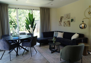 Salon moderne avec table à manger, plantes vertes et canapé à Cube la Mer Wellness près de Kagerplassen.