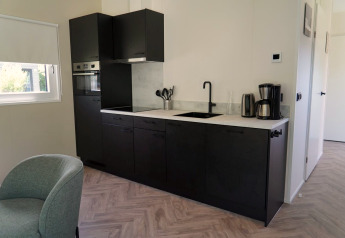 Modern kitchenette at Cube la Mer Wellness at Kagerplassen, Netherlands, with black cabinets and appliances.