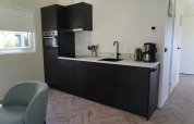 Moderne kitchenette bij Cube la Mer Wellness aan Kagerplassen, Nederland, met zwarte kasten en toestellen.