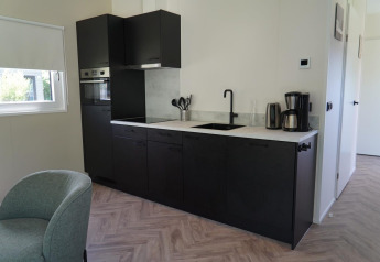 Cocina moderna en Cube la Mer Wellness en Kagerplassen, Países Bajos, con armarios negros y electrodomésticos.