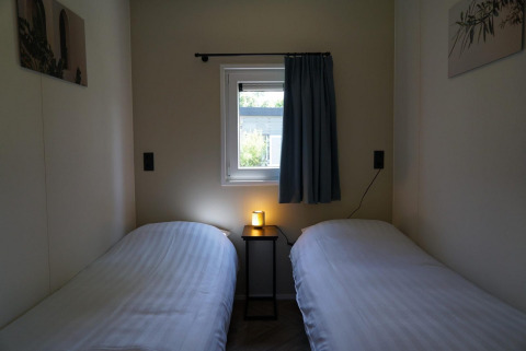 Dos camas individuales con sábanas blancas, mesa pequeña y ventana en Cube la Mer Wellness, Kagerplassen.