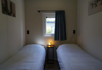 Zwei Einzelbetten mit weißen Laken, kleines Tischchen und Fenster in Cube la Mer Wellness, Kagerplassen.