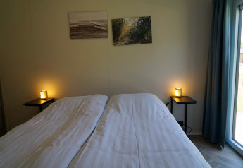Bedroom at Cube la Mer Wellness lodge by Kagerplassen, Netherlands, showing double beds and soft lighting.