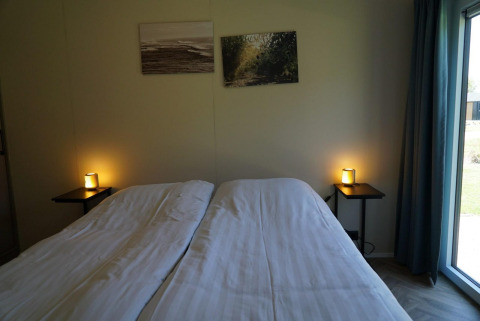 Schlafzimmer im Cube la Mer Wellness Lodge am Kagerplassen, Niederlande, mit Doppelbett und sanfter Beleuchtung.