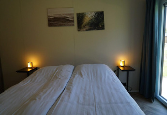 Slaapkamer in Cube la Mer Wellness lodge bij Kagerplassen, Nederland, met twee bedden en sfeerverlichting.