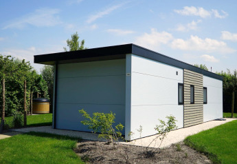 Modern Cube la Mer Wellness lodge at Kagerplassen, Netherlands, with garden and flat roof, sunny day