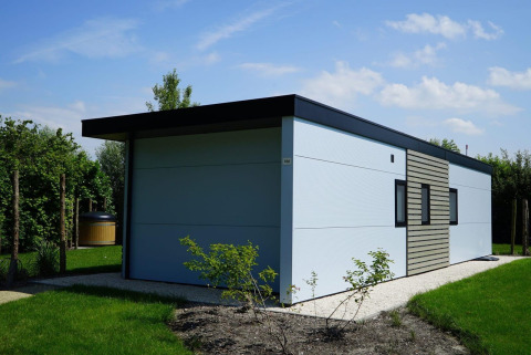 Lodge Cube la Mer Wellness moderne, toit plat et jardin à Kagerplassen, Pays-Bas, sous un ciel ensoleillé