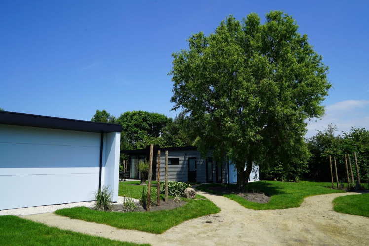 Modernes Ferienhaus und Garten bei Cube la Mer Wellness, Kagerplassen, Niederlande, sonniger Tag.