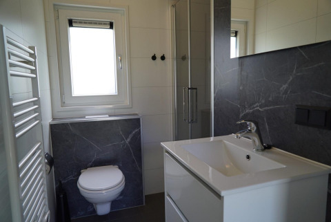 Baño moderno con inodoro suspendido, cabina de ducha y lavabo en Cube la Mer Wellness, Kagerplassen, Países Bajos.