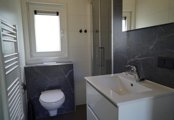 Baño moderno con inodoro suspendido, cabina de ducha y lavabo en Cube la Mer Wellness, Kagerplassen, Países Bajos.