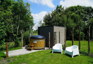 Wellnessbereich im Freien bei Cube la Mer Wellness, Kagerplassen, mit Badefass und weißen Stühlen im Garten.