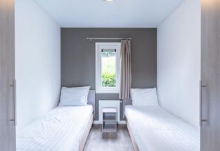 Chambre moderne et lumineuse au Pavilion at Kagerplassen aux Pays-Bas avec deux lits simples et fenêtre centrale.