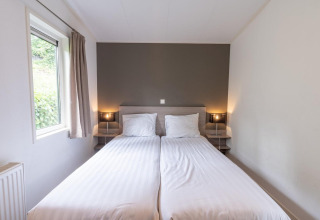 Lichte kamer met twee enkele bedden, een raam en moderne uitstraling in Pavilion aan Kagerplassen, Nederland.