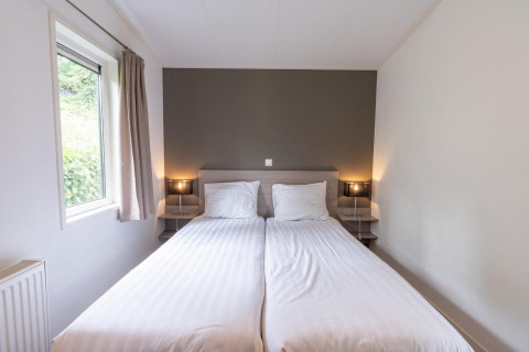 Helles Zimmer mit zwei Einzelbetten, Fenster und moderner Beleuchtung im Pavilion bei Kagerplassen, Niederlande.